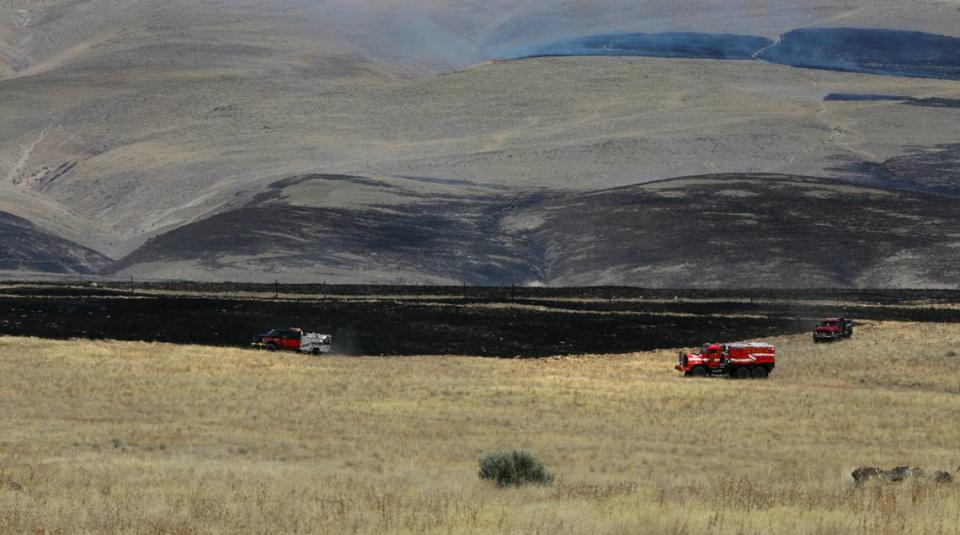 Wildland fire trucks patrol the perimeter of a two-alarm wildfire that forced people from homes Monday afternoon just north of Benton City. There were no immediate details on the size or cause of the blaze.