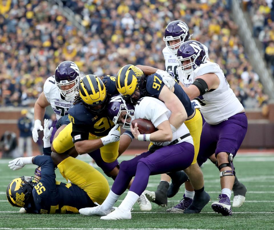 Michigan defensive ends Mike Morris, left, and Aidan Hutchinson sack Northwestern quarterback Ryan Hilinski during the first half on Saturday, Oct.23, 2021, at Michigan Stadium.