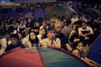 Pro-democracy protestors watch formal talks between student protest leaders and city officials on a video screen near the government headquarters in Hong Kong October 21, 2014. REUTERS/Carlos Barria