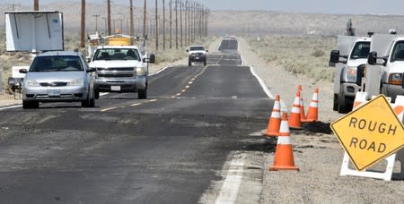 Vehicles drive over a repaired crack that appeared in State Route 178 after an earthquake near Ridgecrest