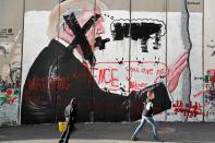 <p>Palestinian children walk past vandalised graffiti depicting President Donald Trump and slogans against Vice President Mike Pence painted on Israel’s controversial separation barrier in the West Bank city of Bethlehem during clashes with Palestinian protestors near an Israeli checkpoint on Dec. 7, 2017. (Photo: Thomas Coex/AFP/Getty Images) </p>