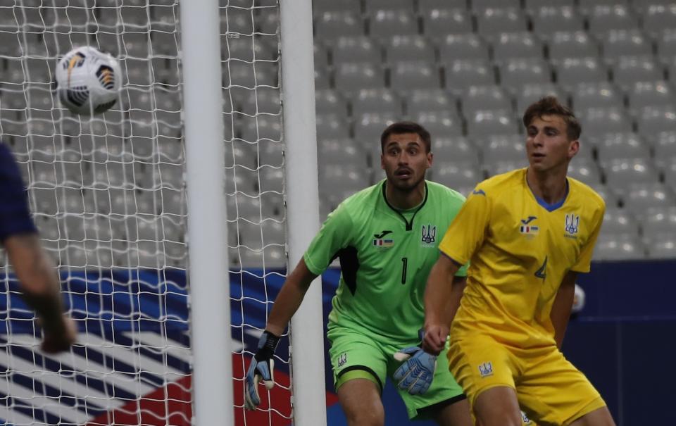 The ball goes into the net ahead as two Ukraine players watch.