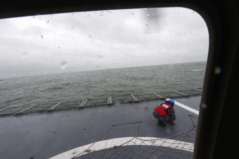 An Indonesian navy sailor crouches as a helicopter takes off from the deck of naval vessel KRI Bung Tomo at sea on January 1, 2015
