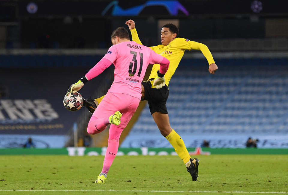 Jude Bellingham tackles goalkeeper Ederson to win the ball.