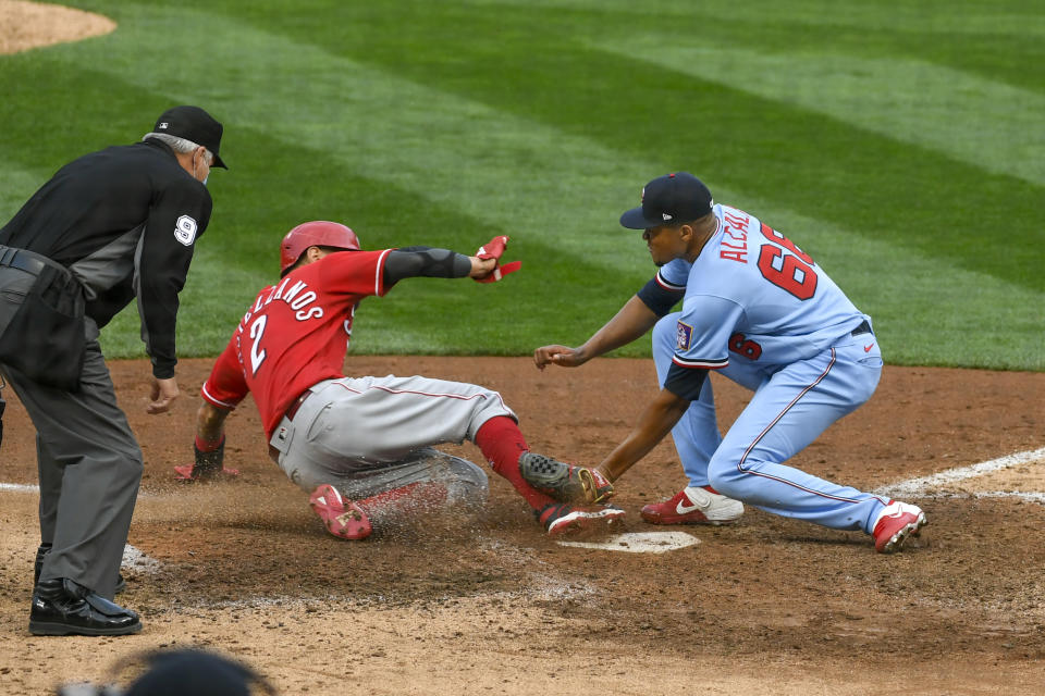 Minnesota Twins pitcher Jorge Alcala, right, tags out Cincinnati Reds' Nick Castellanos as he tries to steal home on a wild pitch during the tenth inning of a baseball game Sunday, Sept. 27, 2020, in Minneapolis. The Reds won 5-3. (AP Photo/Craig Lassig)