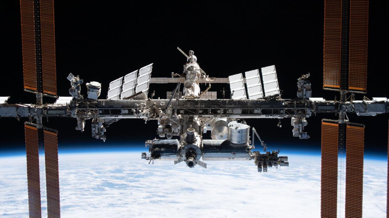  A T-shaped space station floats above Earth. 