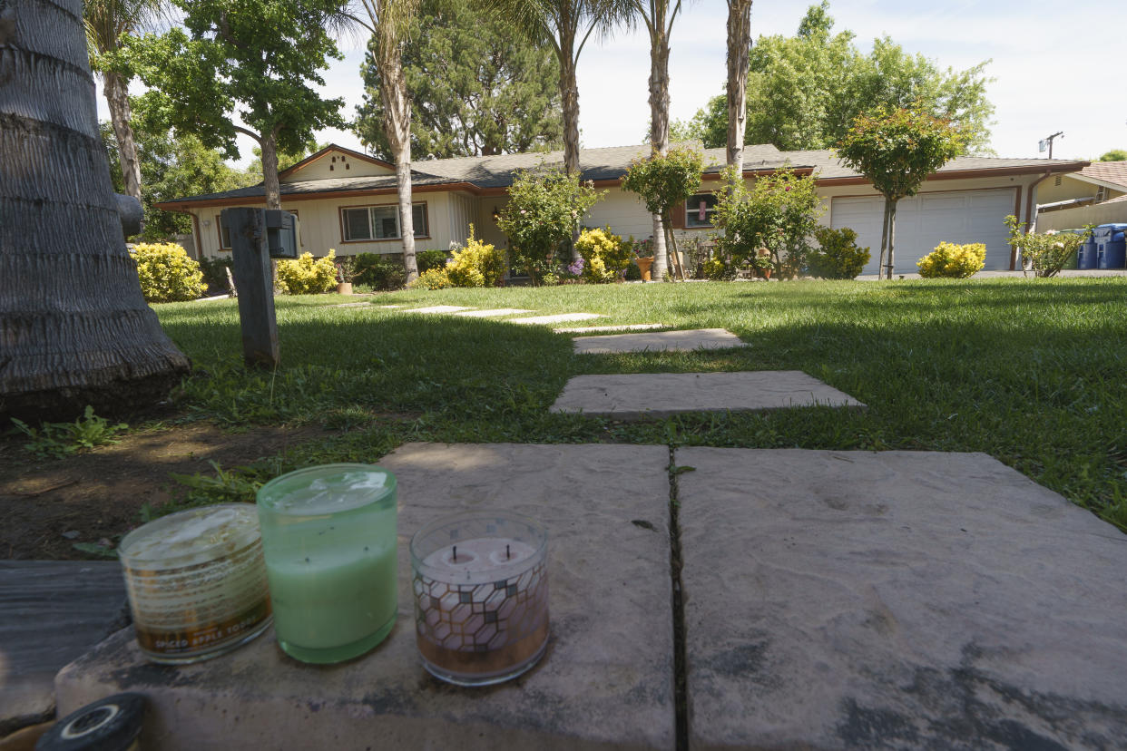 Candles are left on the open front gate of a ranch-style house in the West Hills neighborhood of the San Fernando Valley, in Los Angeles, Monday, May 9, 2022. Police say three children were found dead at the home over the weekend and their mother and a teenager were arrested in the killings. (AP Photo/Damian Dovarganes)