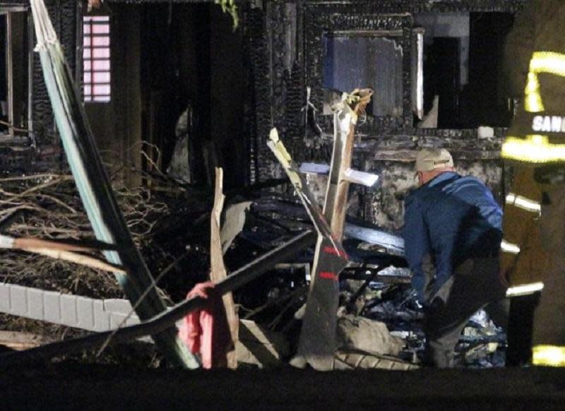 An investigator looks at the charred remains of a small plane that crashed into a house in San Diego: AP