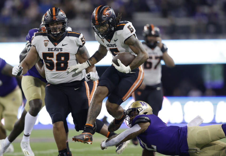 Oregon State running back Damien Martinez (6) leaps from the attempted tackle of Washington linebacker Cam Bright (2) during the first half of an NCAA college football game Friday, Nov. 4, 2022, in Seattle. (AP Photo/John Froschauer)