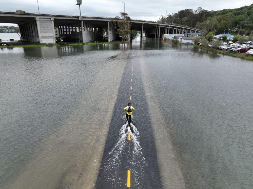 An aerial picture shows a cyclist riding through a flooded bike path in Mill Valley during a king tide in 2022.