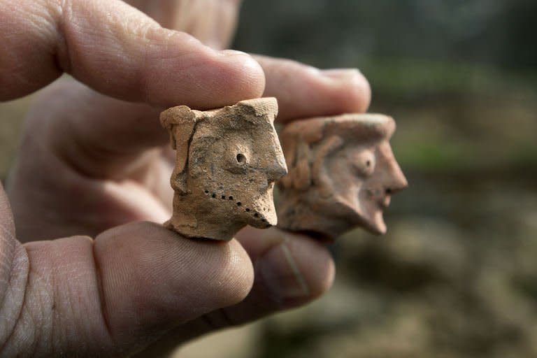 An Israel Antiquities Authority archeologist displays on December 26, 2012 clay figurines used for religious rituals and practices, dated to the early monarchic period (9-10th century. BC) of the Judaean monarchy, uncovered in Tel Motza near Jerusalem during rescue excavations