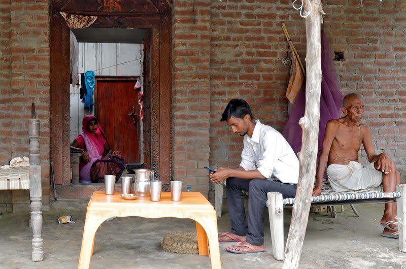 Ashish Kumardia checks his mobile phone outside his house in Dutta Nagar