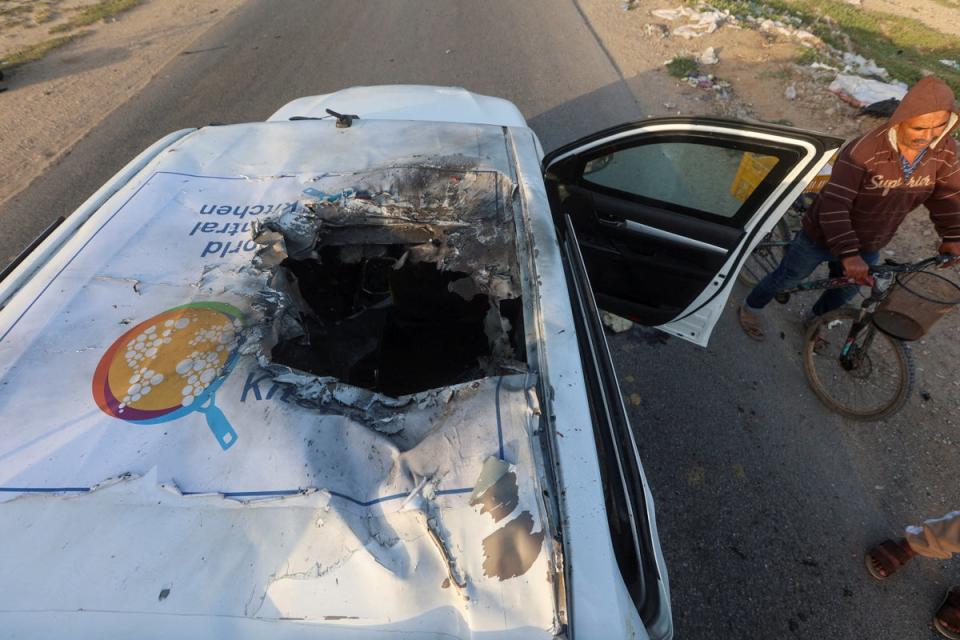 A Palestinian man rides a bicycle past a damaged vehicle where employees from the World Central Kitchen (WCK), including foreigners, were killed in an Israeli airstrike amid the ongoing conflict between Israel and Hamas, in Deir Al-Balah, in central Gaza Strip on 2 April 2024 (REUTERS)