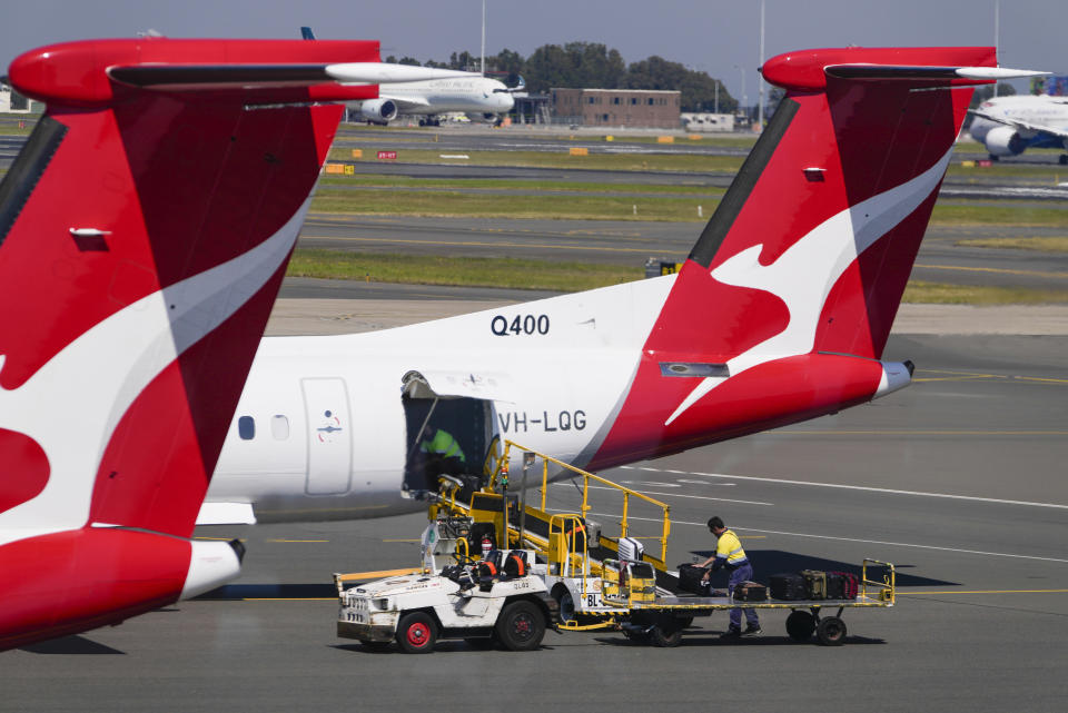 Baggage handlers work near a Qantas plane at Sydney's domestic terminal. 