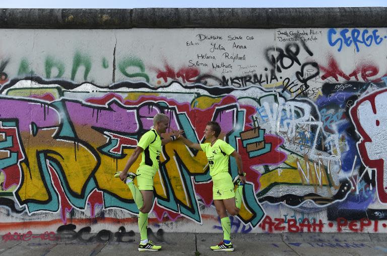 Martina Schliep and her partner Gaston Pruefer stretch beside the old Berlin Wall on August 11, 2014 as they train for the "100MeilenBerlin" marathon event