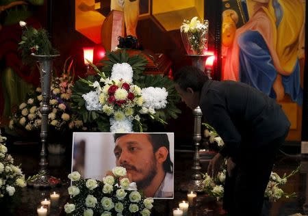 A relative of photojournalist Ruben Espinosa stands next to his coffin and a picture of him during the wake in Mexico City, Mexico August 2, 2015. REUTERS/Henry Romero