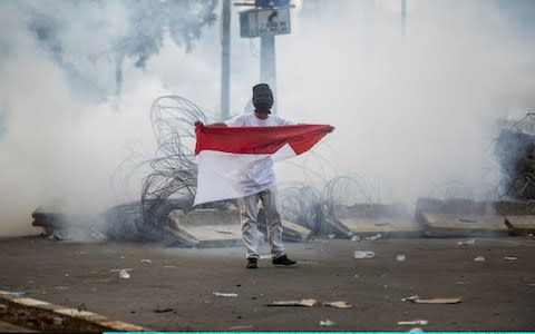 A student holds an Indonesian flag at a rally outside the parliament - Credit: Getty Images/Oscar Siagian