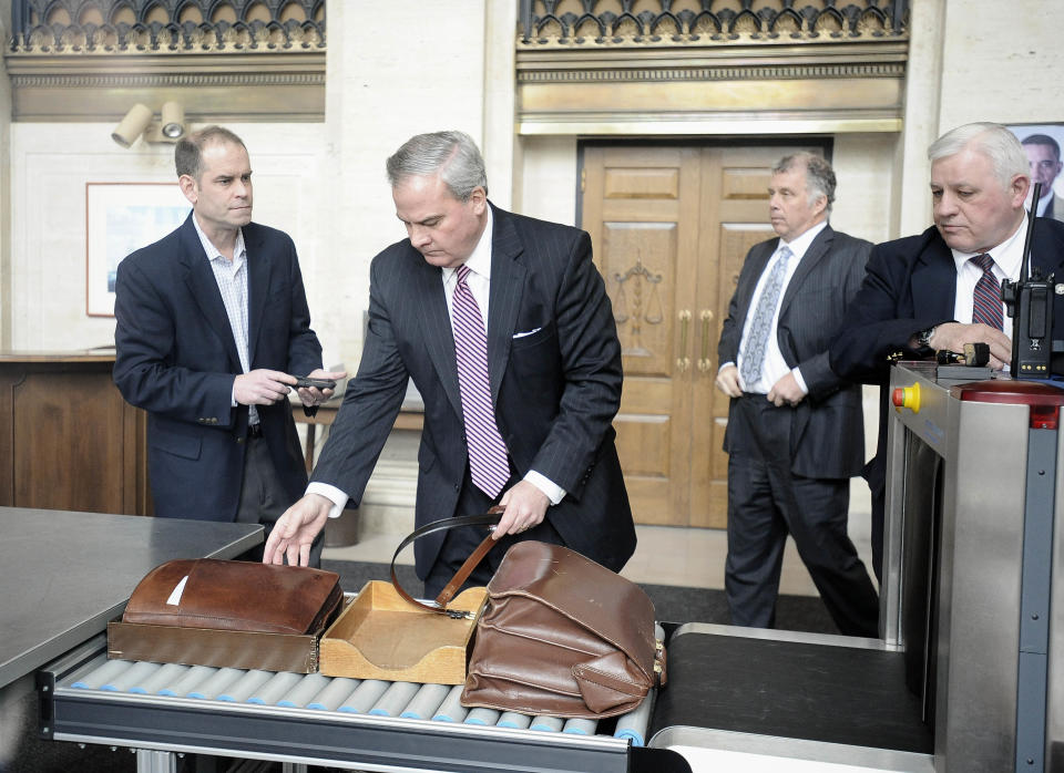 Former Connecticut Gov. John G. Rowland collects his belt and brief case after going through security at federal court, Friday, April 11, 2014, in New Haven, Conn. A grand jury on Thursday returned a seven-count indictment alleging Rowland schemed to conceal involvement with congressional campaigns. (AP Photo/Jessica Hill)