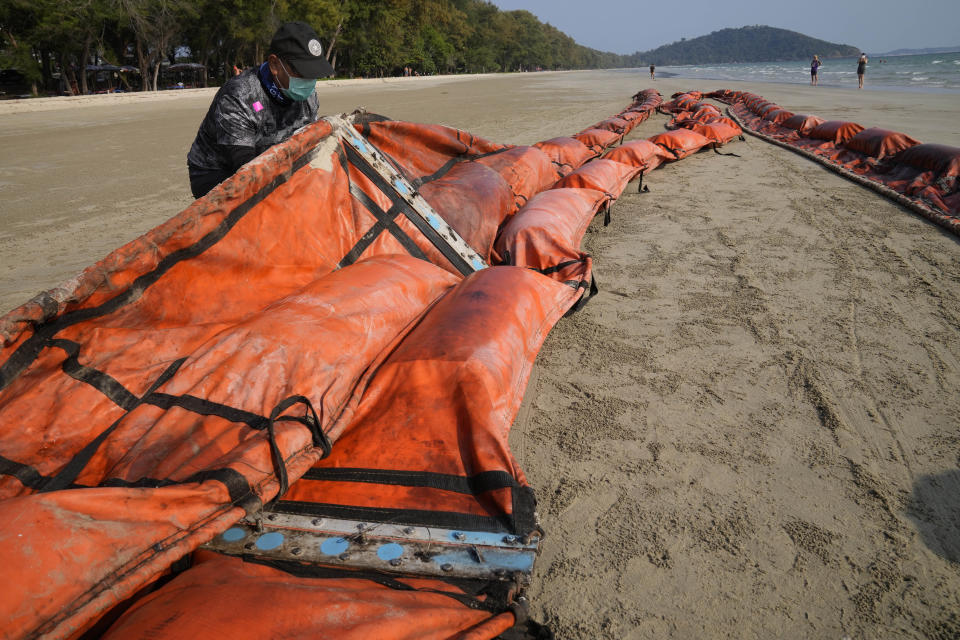 Workers prepare an oil spill boom on Mae Ram Phueng Beach in hopes of containing any oil from a recent spill off the coast of Rayong, eastern Thailand, Friday, Jan. 28, 2022. An oil slick off the coast of Thailand continued to expand Friday and was approaching beaches on the east coast, home to fragile coral and seagrass, officials said. (AP Photo/Sakchai Lalit)