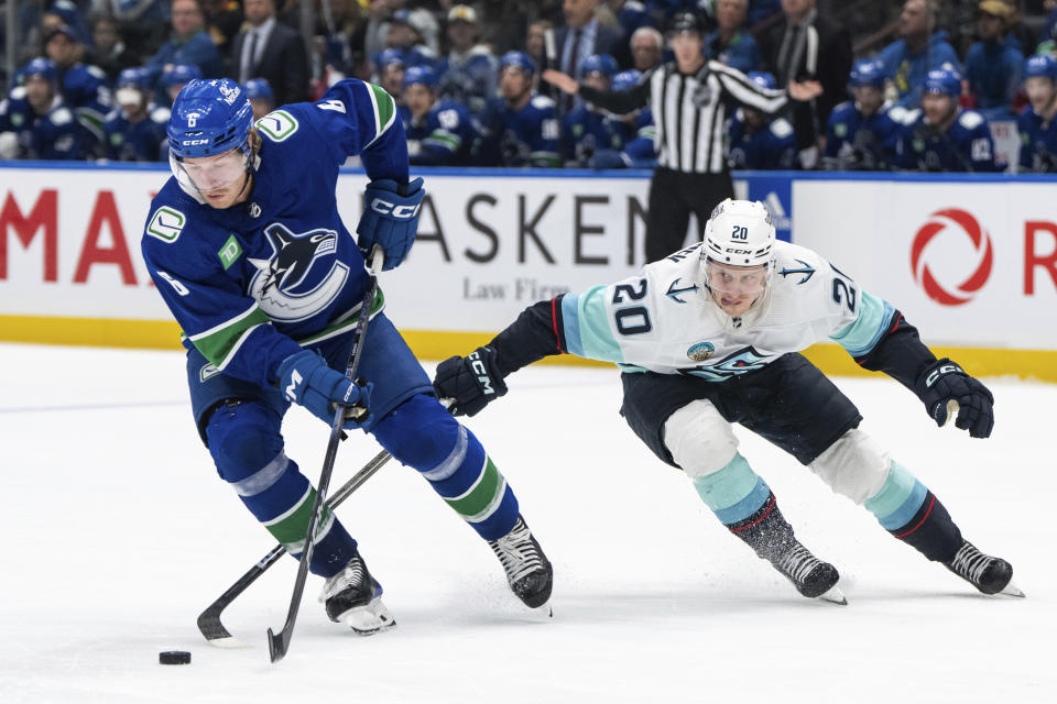 Vancouver Canucks' Brock Boeser (6) and Seattle Kraken's Eeli Tolvanen (20) vie for the puck during the third period of an NHL hockey game Saturday, Nov. 18, 2023, in Vancouver, British Columbia. (Ethan Cairns/The Canadian Press via AP)