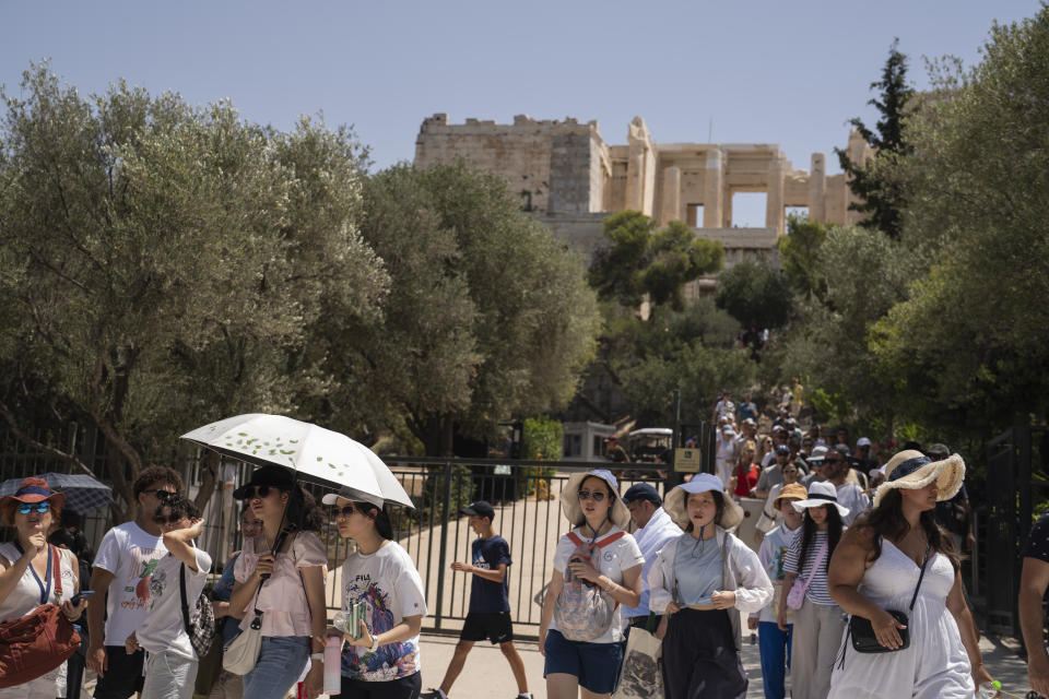 Tourists exit the ancient Acropolis of Athens as the Greek culture ministry shut down the monument most of the day because of heat, Friday, July 14, 2023. Temperatures were starting to creep up in Greece, where a heatwave was forecast to reach up to 44 degrees Celsius in some parts of the country over the weekend. (AP Photo/Petros Giannakouris)