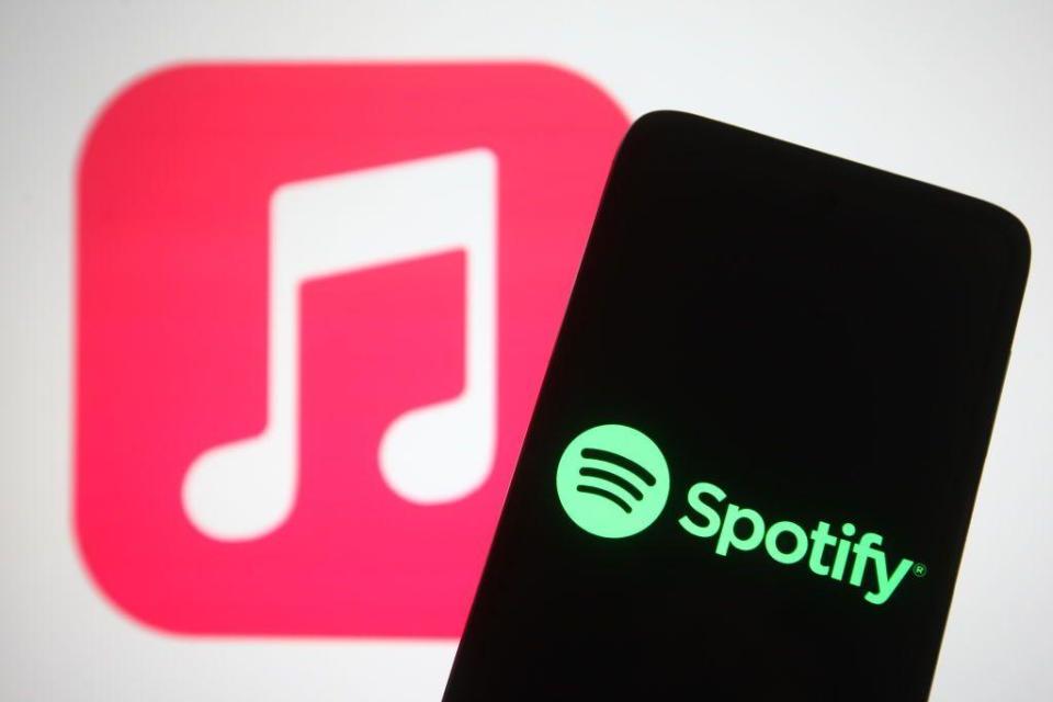 Un teléfono con el logo de Spotify delante del logo de Apple Music