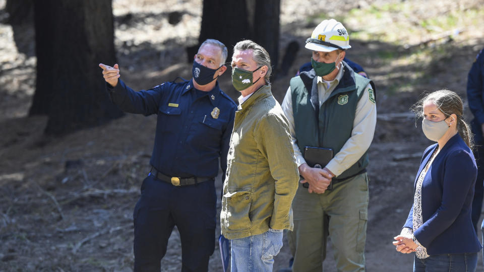 Gov. Gavin Newsom meets with local fire officials while touring an area burned by last year's Creek Fire near Shaver Lake in Fresno County, Calif., Thursday, April 8, 2021. California will authorize $536 million for wildfire mitigation and forest management projects before the worst of the fire season strikes later this year, Newsom and legislative leaders said Thursday. (Craig Kohlruss/The Fresno Bee via AP)