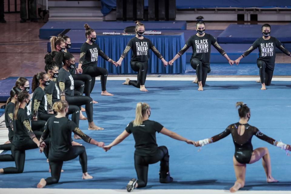 UCLA gymnasts join hands during a prematch ceremony.