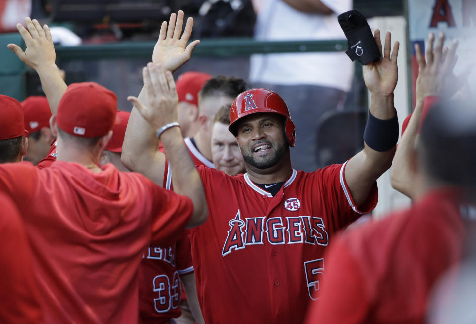 Los Angeles Angels' Albert Pujols, center, is greeted in the dugout after scoring on a double by David Fletcher during the fourth inning of the tema's baseball game against the Pittsburgh Pirates on Wednesday, Aug. 14, 2019, in Anaheim, Calif. (AP Photo/Marcio Jose Sanchez)