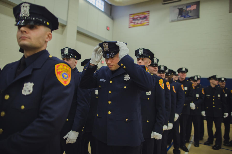 Matias Ferreira, center, adjusts his hat during his graduation ceremony from the Suffolk County Police Department Academy at the Health, Sports and Education Center in Suffolk, Long Island, New York, Friday, March 24, 2017. Ferreira, a former U.S. Marine Corps lance corporal who lost his legs below the knee when he stepped on a hidden explosive in Afghanistan in 2011, is joining a suburban New York police department. The 28-year-old graduated Friday from the Suffolk County Police Academy on Long Island following 29 weeks of training. (AP Photo/Andres Kudacki)