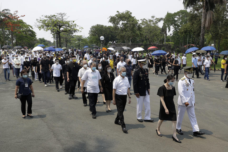 The family of former Philippine President Benigno Aquino III march during state burial rites on Saturday, June 26, 2021 at a memorial park in suburban Paranaque city, Philippines. Aquino was buried in austere state rites during the pandemic Saturday with many remembering him for standing up to China over territorial disputes, striking a peace deal with Muslim guerrillas and defending democracy in a Southeast Asian nation where his parents helped topple a dictator. He was 61. (AP Photo/Aaron Favila)