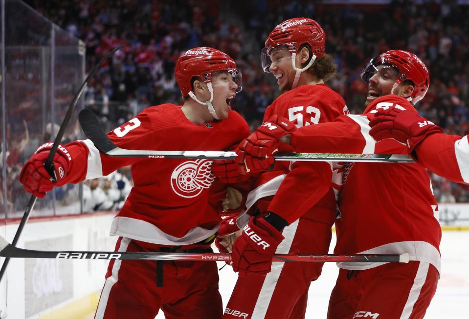 Detroit Red Wings left wing Lucas Raymond, left, celebrates with defenseman Moritz Seider (53) and left wing David Perron, right, after scoring against the Tampa Bay Lightning during the first period of an NHL hockey game Sunday, Jan. 21, 2024, in Detroit. (AP Photo/Duane Burleson)