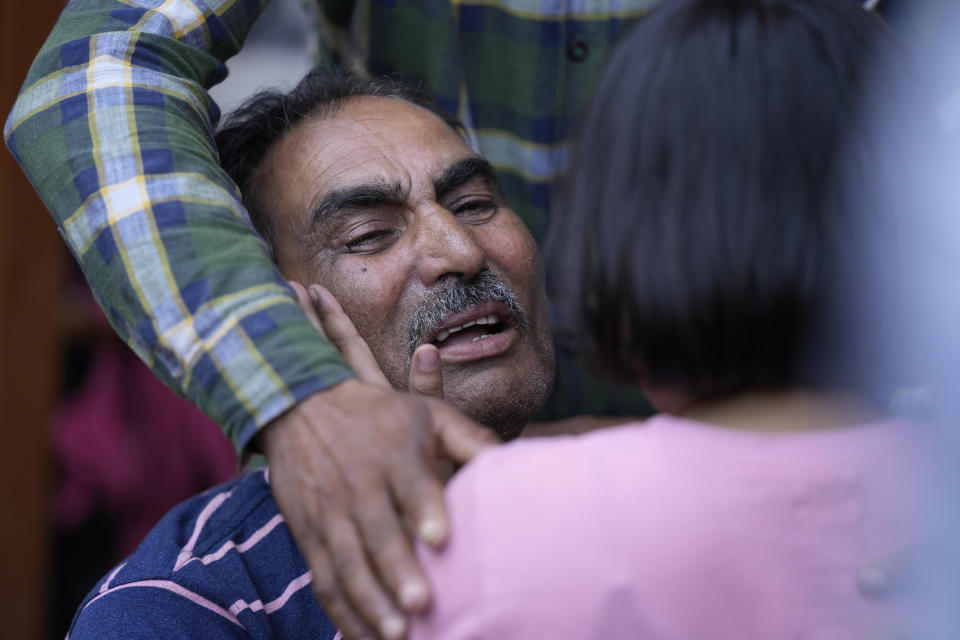 A child consoles the father of Rahul Bhat, a government employee killed on Thursday, in Jammu, India, Friday, May 13, 2022. Bhat, who was a minority Kashmiri Hindu known as "pandits," was killed by suspected rebels inside his office in Chadoora town in the Indian portion of Kashmir. (AP Photo/Channi Anand)