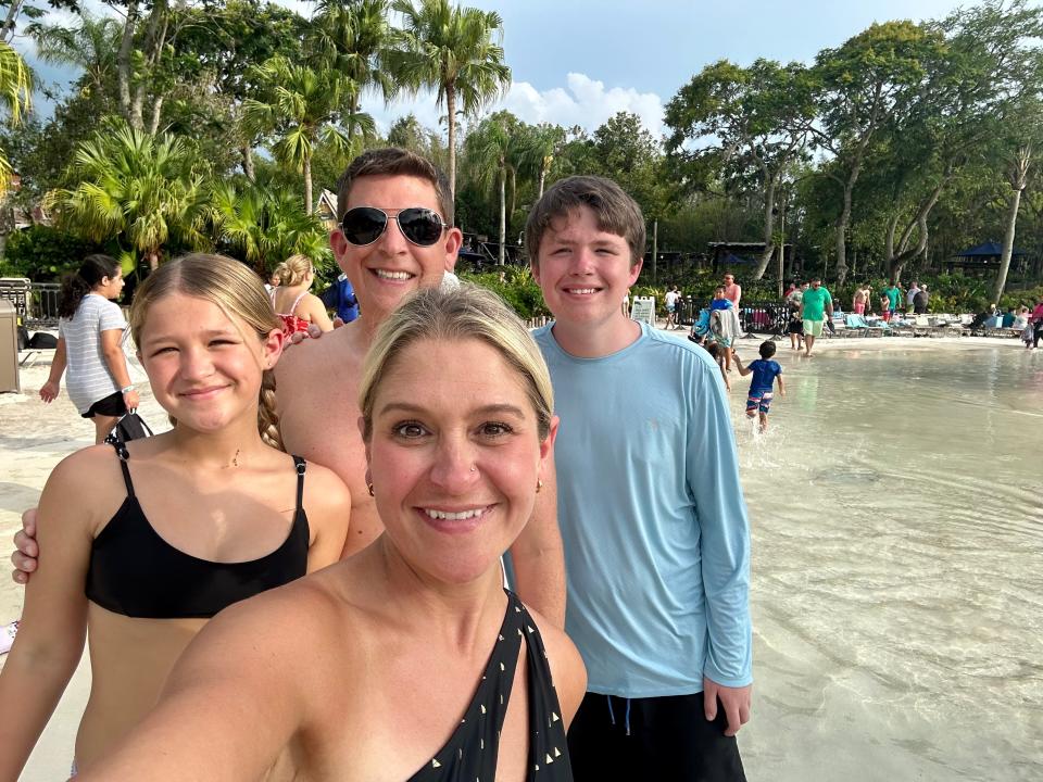 The writer, her husband, and two teenagers smiling for a selfie on a sandy area