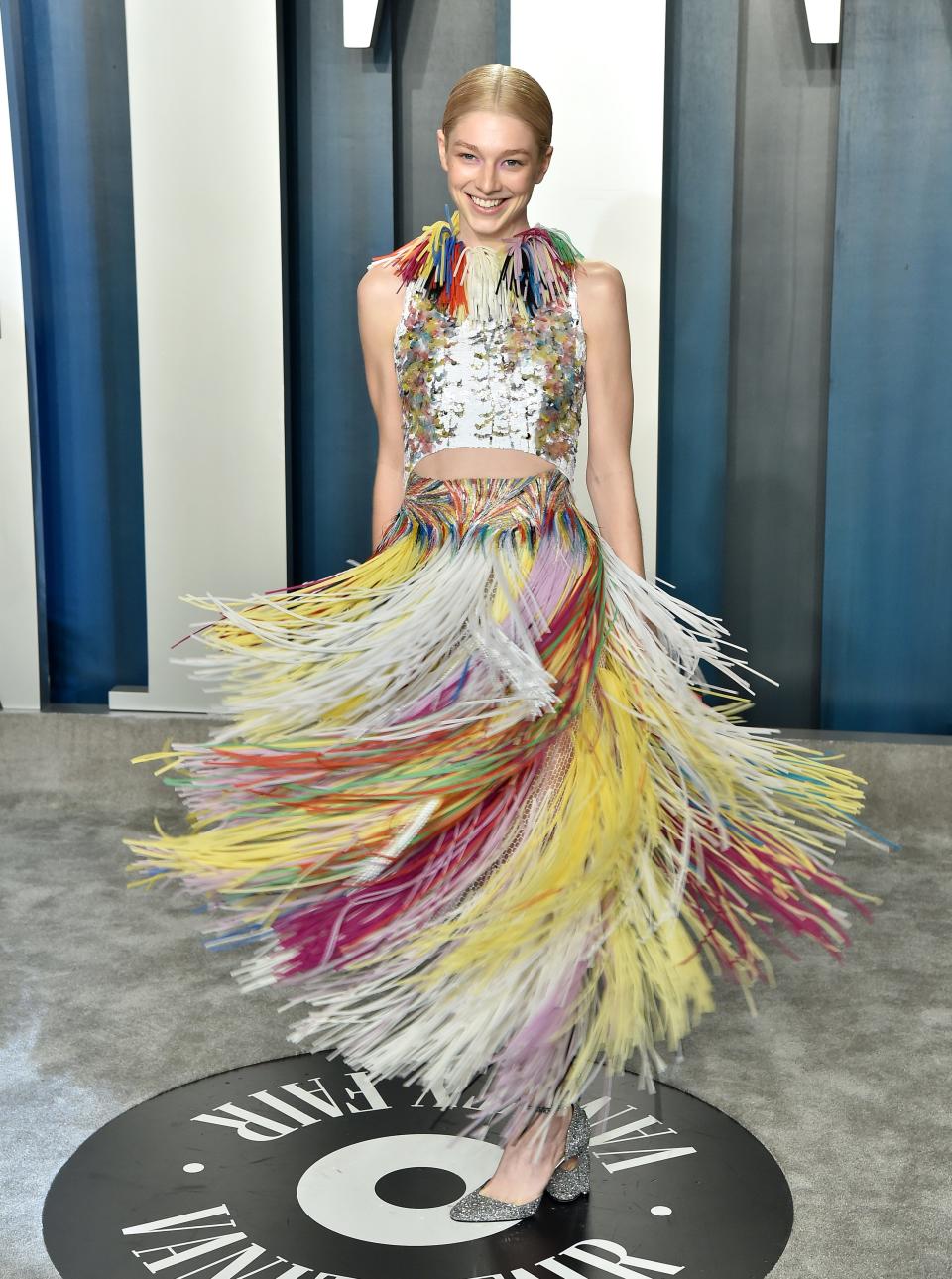 Hunter in a metallic halter top with colorful fringe on the shoulders and a matching flowing colorful fringe skirt.