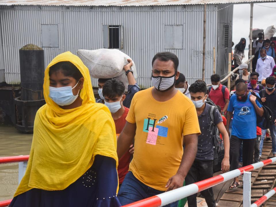 People wearing facemasks arrive at Launch station in the River Padma as they return back in capital city after end of their Eid al-Adha holidays in Dhaka, Bangladesh on August 5, 2020 (Photo by Mamunur Rashid/NurPhoto via Getty Images)