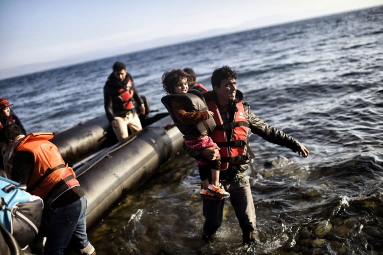 A migrant carries a child as refugees and migrants arrive on the Greek island of Lesbos after crossing the Aegean sea from Turkey on October 5, 2015