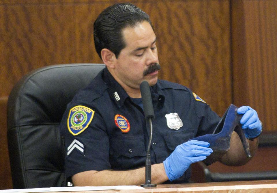 Houston police officer Ernest Aguilera examines a stiletto shoe entered into evidence during the trial against Ana Lilia Trujillo Tuesday, April 1, 2014, in Houston. Trujillo, 45, is charged with murder, accused of killing her 59-year-old boyfriend, Alf Stefan Andersson with the heel of a stiletto shoe, at his Museum District high-rise condominium in June 2013. (AP Photo/Houston Chronicle, Brett Coomer) MANDATORY CREDIT