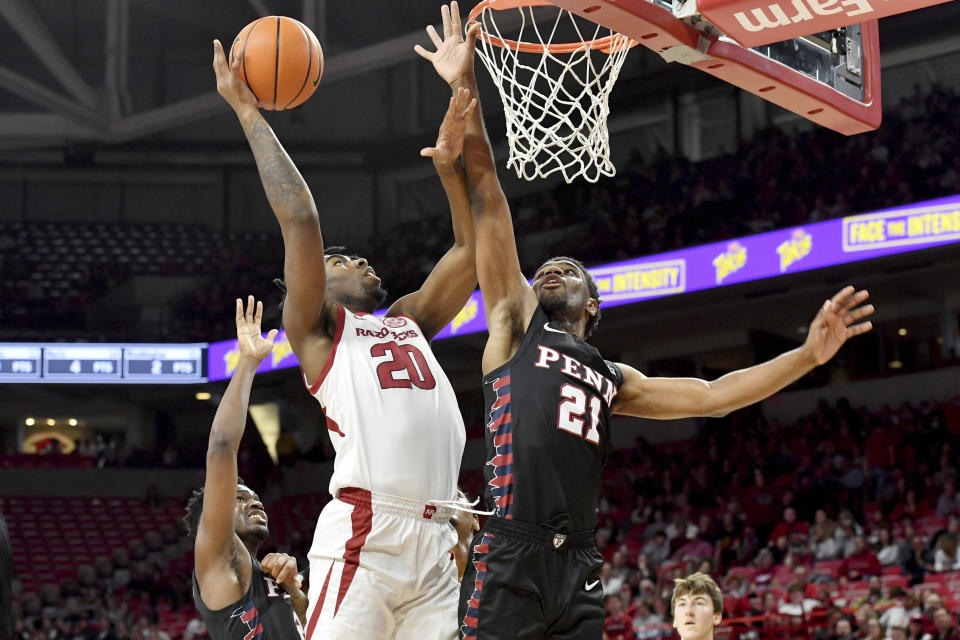 Arkansas forward Kamani Johnson (20) drives past Pennsylvania defenders Jonah Charles (2) and Bryce Washington (21) during the first half of an NCAA college basketball game Sunday, Nov. 28, 2021, in Fayetteville, Ark. (AP Photo/Michael Woods)