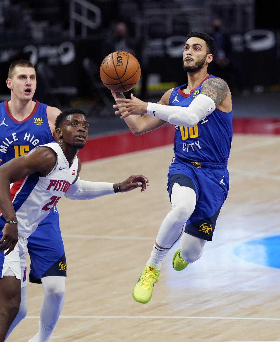 Denver Nuggets guard Markus Howard (00) makes a layup next to Detroit Pistons forward Tyler Cook (25) during the first half of an NBA basketball game, Friday, May 14, 2021, in Detroit. (AP Photo/Carlos Osorio)