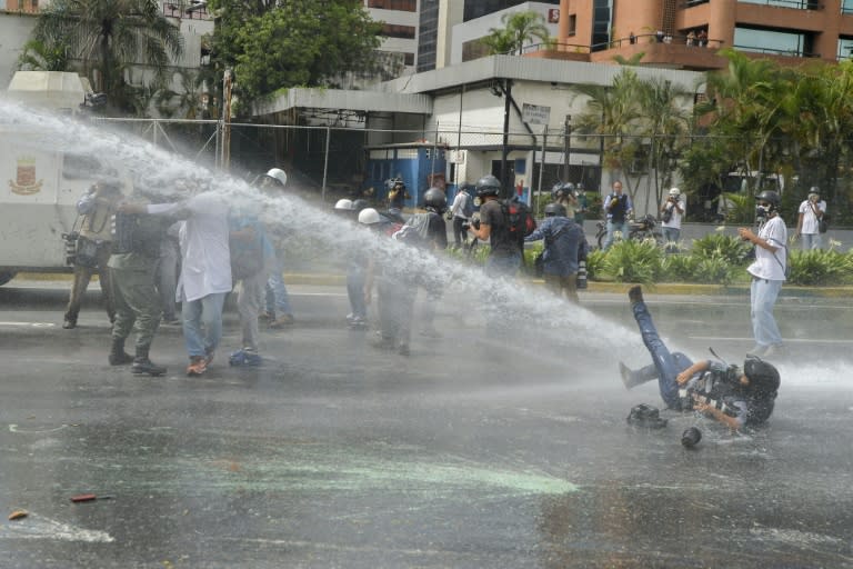 AP photographer Ariana Cubillos is knocked down by the water jet of a riot control vehicle as opposition activists clash with riot police during a health care personnel march in Caracas on May 22, 2017