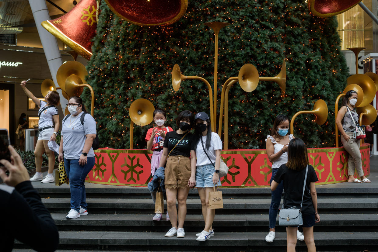 People pose with a Christmas Tree along Singapore's Orchard Road shopping district as it filled with crowds on Sunday, 12 December 2021. (Photo by Joseph Nair/NurPhoto via Getty Images)