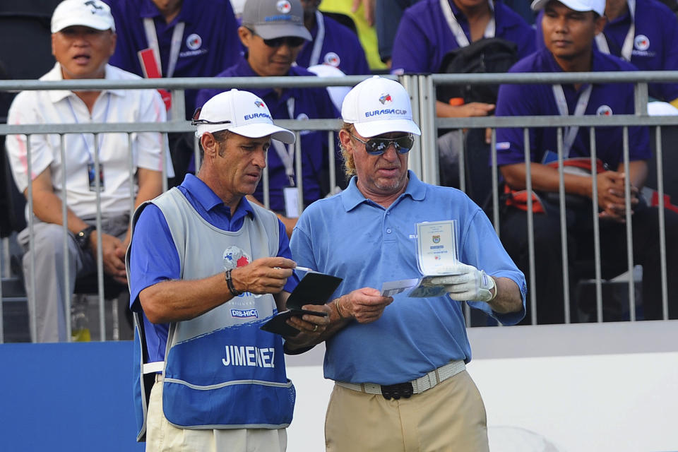 Spain's Miguel Angel Jimenez, right, listens to his caddy before teeing off on the first hole during the first round of the Eurasia Cup golf tournament at the Glenmarie Golf and Country Club in Subang, Malaysia, Thursday, March 27, 2014. (AP Photo/Joshua Paul)