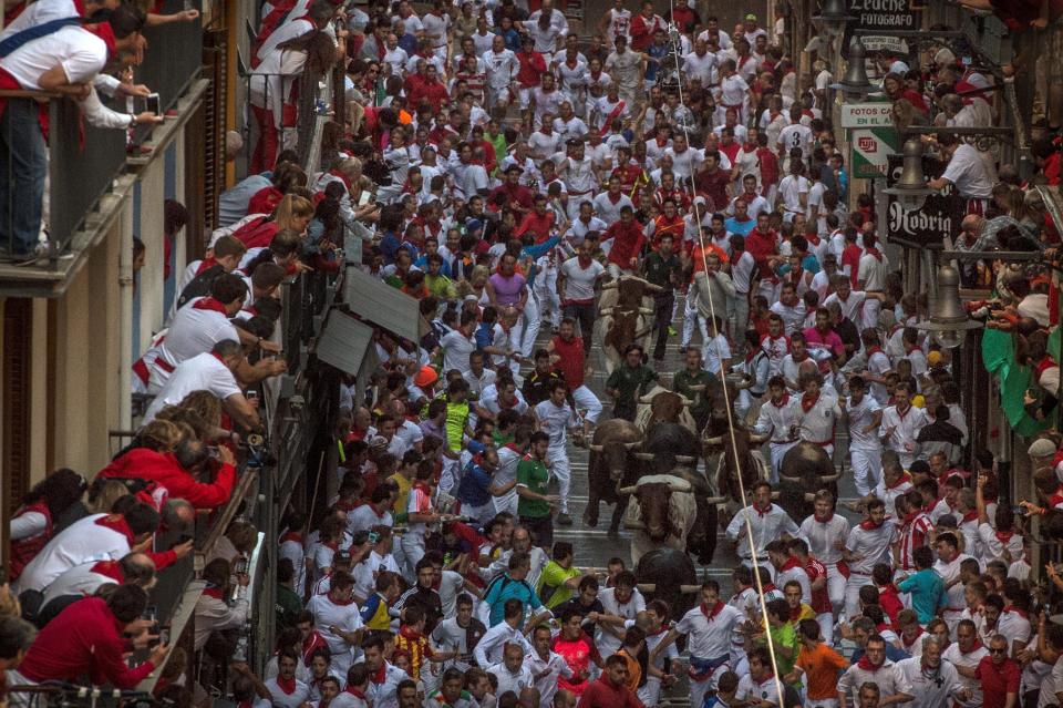 PAMPLONA, SPAIN - JULY 09:  Revellers run with the Victoriano del Rio Cortes' fighting bulls along Estafeta street during the fourth day of the San Fermin Running of the Bulls festival on July 9, 2015 in Pamplona, Spain. The annual Fiesta de San Fermin, made famous by the 1926 novel of US writer Ernest Hemmingway entitled 'The Sun Also Rises', involves the daily running of the bulls through the historic heart of Pamplona to the bull ring.  (Photo by David Ramos/Getty Images)