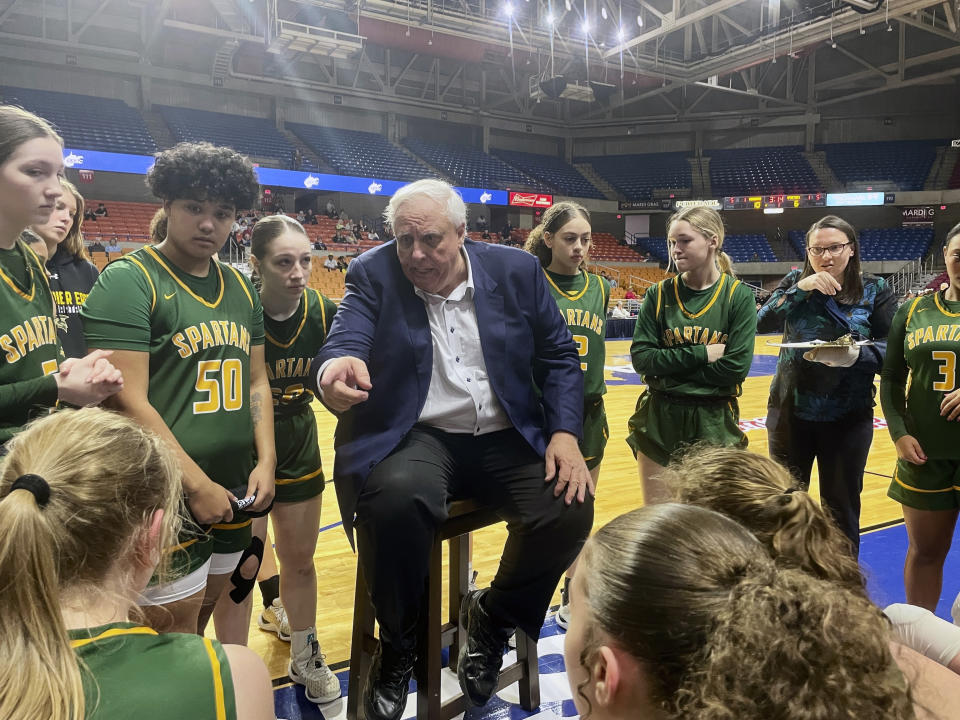 West Virginia Gov. Jim Justice, who is also the coach of the Greenbrier East High School girls basketball team, talks to his players during a timeout at the state tournament Tuesday, March 5, 2024, in Charleston, W.Va. (AP Photo/John Raby)