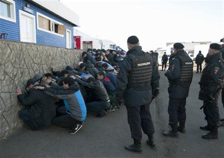 Russian police detain migrant workers during a raid at a vegetable warehouse complex in the Biryulyovo district of Moscow October 14, 2013. REUTERS/Ivan Stolpnikov