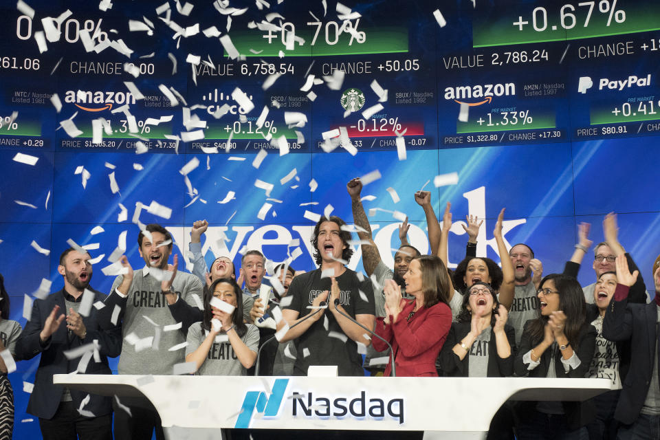 Adam Neumann, center, co-founder and CEO of WeWork, attends the opening bell ceremony at Nasdaq, Tuesday, Jan. 16, 2018, in New York. WeWork is a privately held shared workspace company based in New York. (AP Photo/Mark Lennihan)