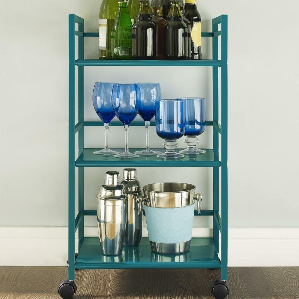 Bar cart with bottles, glasses, and accessories in a living room setting with a sofa and a TV