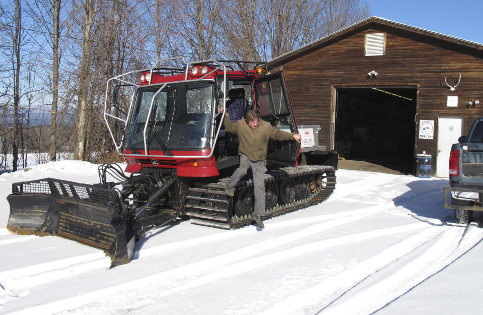 Barre Sno-Bees Snowmobile Club Trailmaster Tim Stone stands in front of the tractor the club uses to pull trail grooming equipment, Wednesday, Jan. 22, 2014, in Barre, Vt. Below-zero temperatures are being reported across Vermont but unlike most of New England and parts of the mid-Atlantic, heavy snow continues to evade the state. (AP Photo/Wilson Ring)