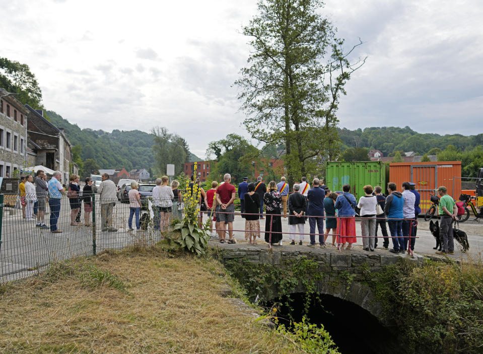 Residents and officials stand for a moment of silence after a wreath laying ceremony in Nessonvaux, Belgium, on Thursday, July 14, 2022. Commemorations were held on Thursday to pay homage to the victims of catastrophic flooding in several provinces of Belgium after torrential rains fell in the region one year ago. (AP Photo/Virginia Mayo)